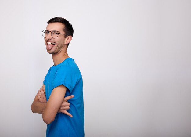 Un joven alegre muestra su lengua en un blanco.