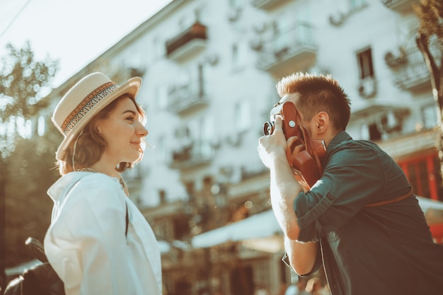 Joven alegre pareja de hipsters son fotografiados en una cámara retro mientras camina por la ciudad.