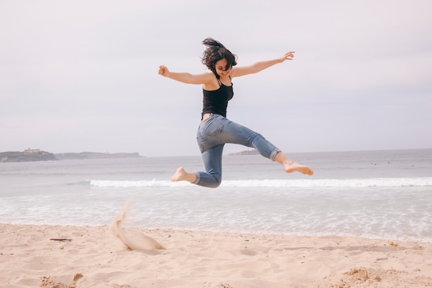 Joven alegre saltando en la playa