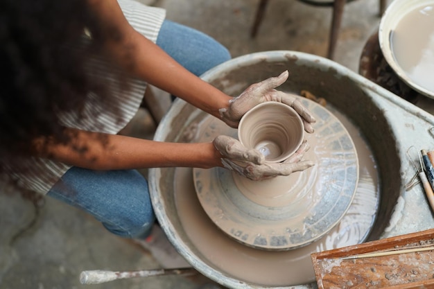 Joven alfarero de mano haciendo jarrón de arcilla en el taller de cerámica