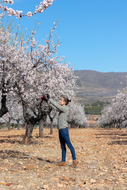 Joven en almendro con paisaje rural en el fondo