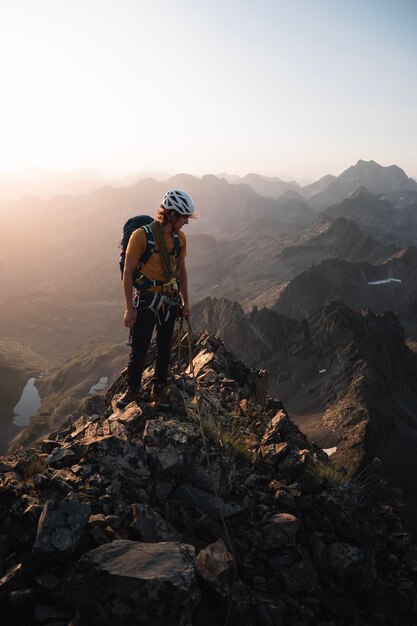 Foto un joven alpinista disfruta del paisaje de los pirineos durante un hermoso y cálido amanecer de verano mientras sube a una cresta rocosa alpina