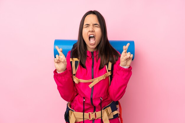 Joven alpinista con una mochila grande con cruzar los dedos