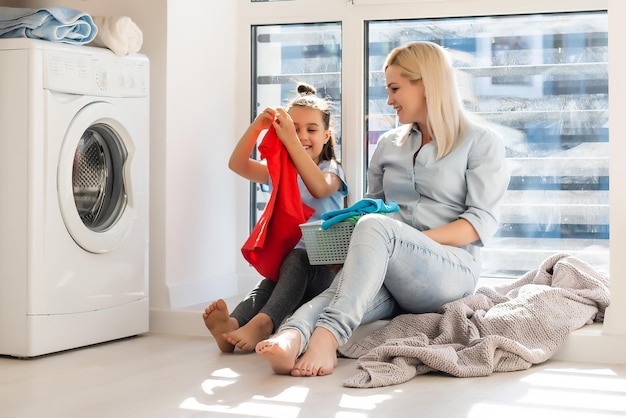 Joven ama de casa y niña lavando la ropa juntos