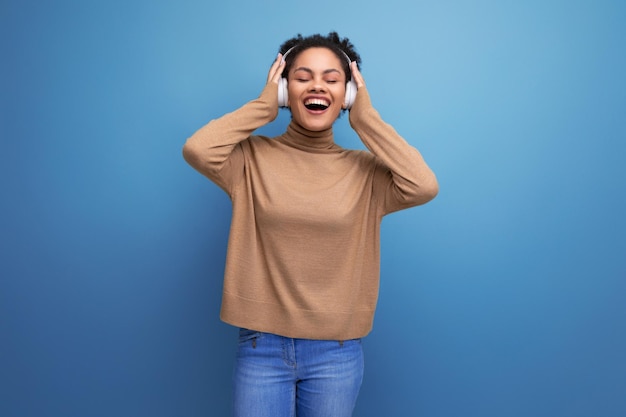 Joven amante de la música latina feliz con el pelo rizado aislado fondo de estudio con espacio de copia