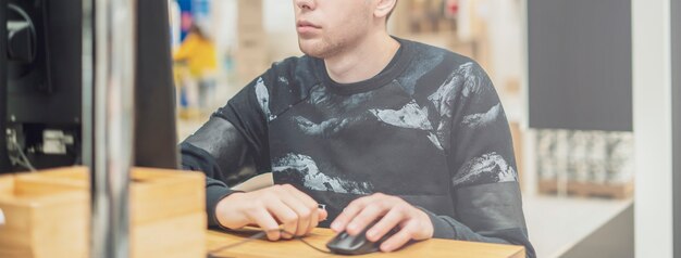 Joven ambicioso en casual trabajando en una computadora en la oficina