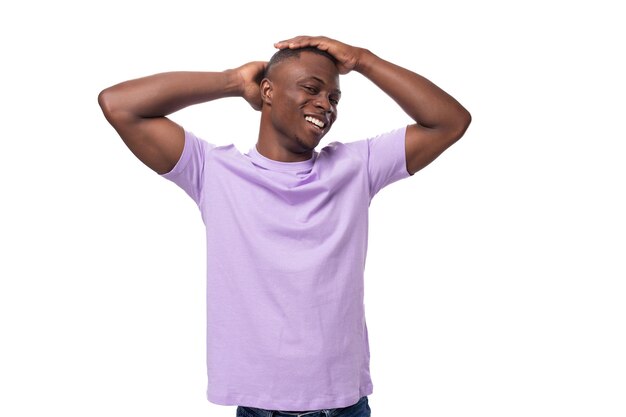 Un joven americano auténtico vestido con una camiseta de lila clara está seguro de sí mismo en un blanco