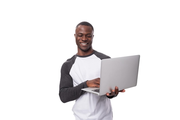 Joven americano vestido casualmente trabajando usando una computadora portátil
