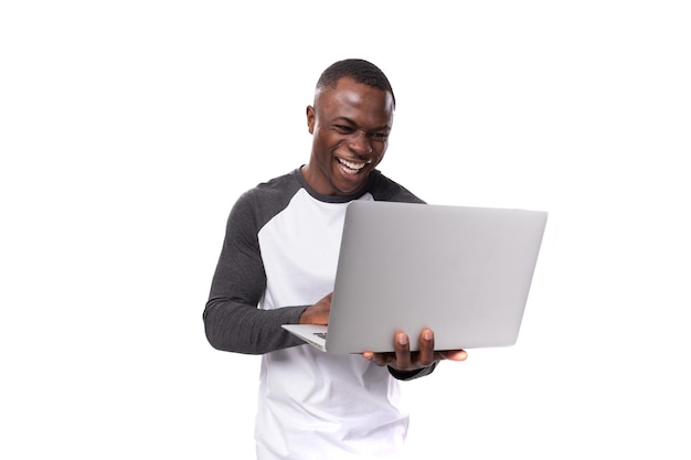 Joven americano vestido casualmente trabajando usando una computadora portátil