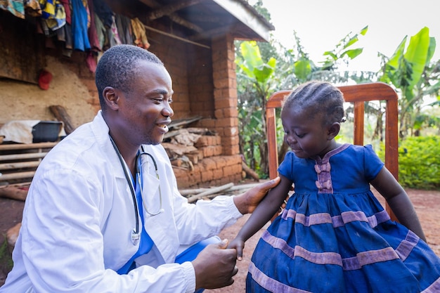 Un joven y amigable pediatra visitando a una niña enferma en el pueblo
