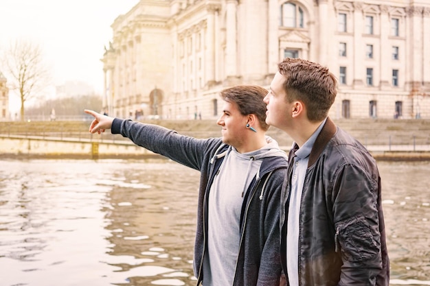 Un joven con un amigo apuntando al río en la ciudad