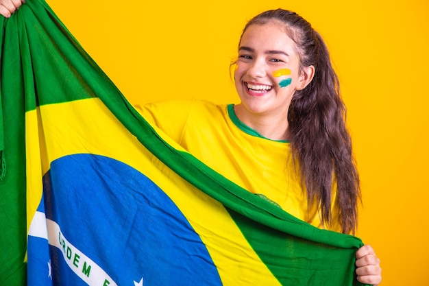 Joven animadora brasileña con una bandera de brasil sonriendo felizmente