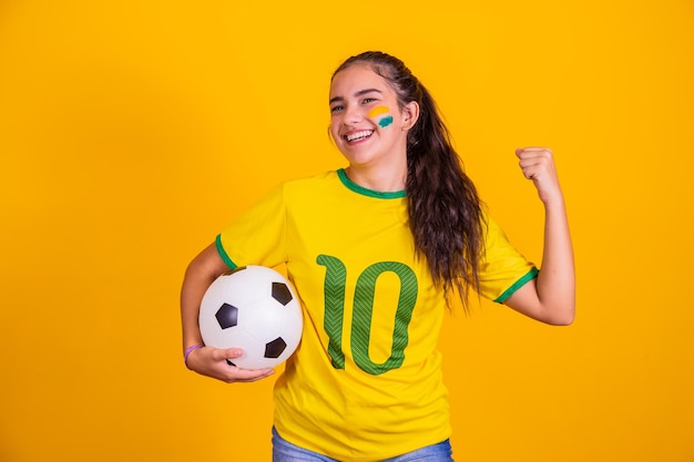 Joven animadora brasileña con una pelota en la mano y cara pintada