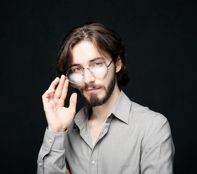 Joven con anteojos sobre fondo negro Concepto de estilo de vidaCerrar