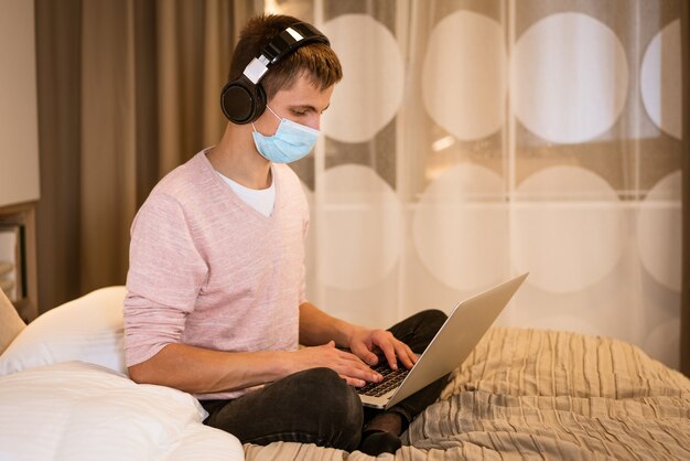 Foto un joven de apariencia europea en ropa casual se sienta en una cama en una habitación en su casa vistiendo headpho ...