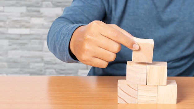 Joven apilando bloques de madera. Bloque de madera en blanco para insertar alguna oración, icono, símbolo. Concepto de desarrollo empresarial.