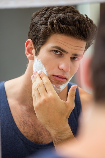 Joven aplicando espuma de afeitar en la cara