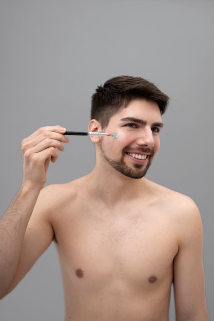 Joven aplicando loción brillante en su rostro