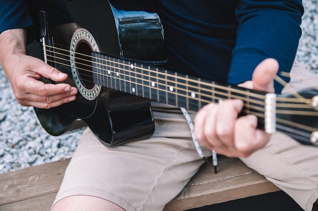 Joven aprende a tocar la guitarra en las calles de la ciudad. Estilo de vida. Foto de alta calidad