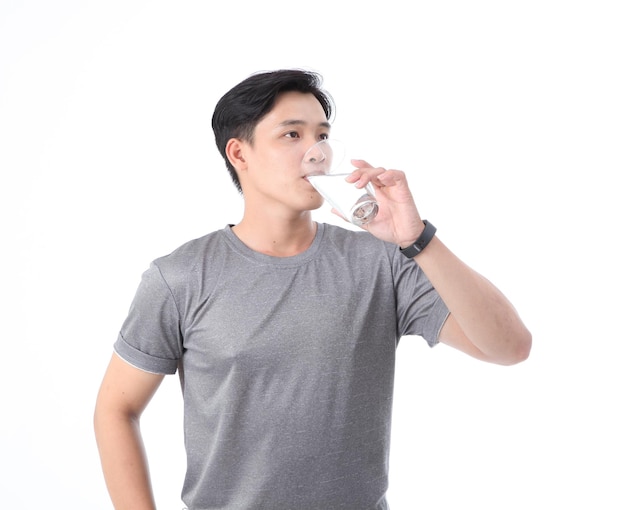 Un joven apuesto y alegre, deportivo asiático, con un vaso de agua potable aislado en el fondo