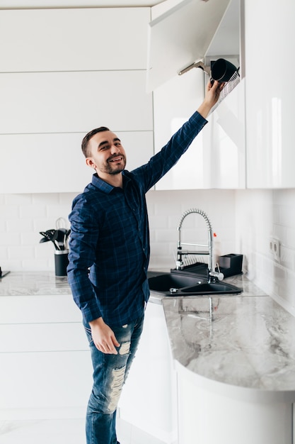 Joven apuesto almacenamiento abierto en la cocina