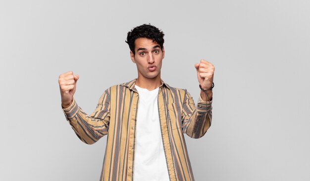 Joven apuesto celebrando un éxito increíble como un ganador, luciendo emocionado y feliz diciendo ¡toma eso!