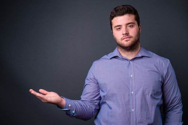 Foto joven apuesto empresario barbudo con sobrepeso en gris