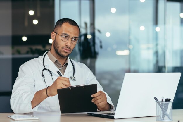 Un joven apuesto, un estudiante latinoamericano, un médico en prácticas, un pasante estudia a través de un enlace de video de