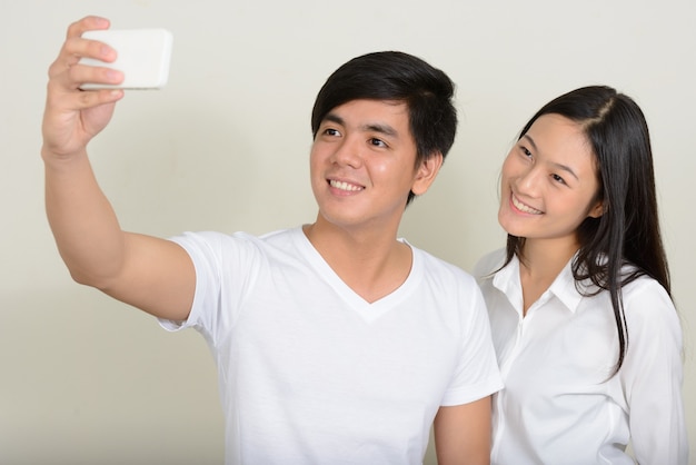 Foto joven apuesto filipino y joven y bella mujer asiática juntos en blanco