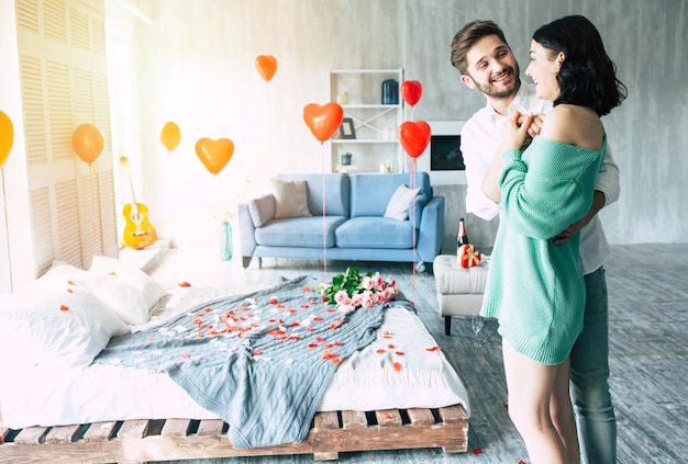 Un joven apuesto le hace una propuesta a su bella novia para que se case con él en un hermoso dormitorio con un trasfondo romántico. Esposo y esposa