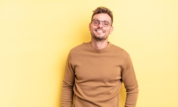 Joven apuesto hispano sonriendo alegre y casualmente con una expresión positiva, feliz, segura y relajada