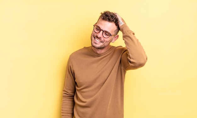 Joven apuesto hispano sonriendo alegre y casualmente, tomando mano a mano con una mirada positiva, feliz y segura