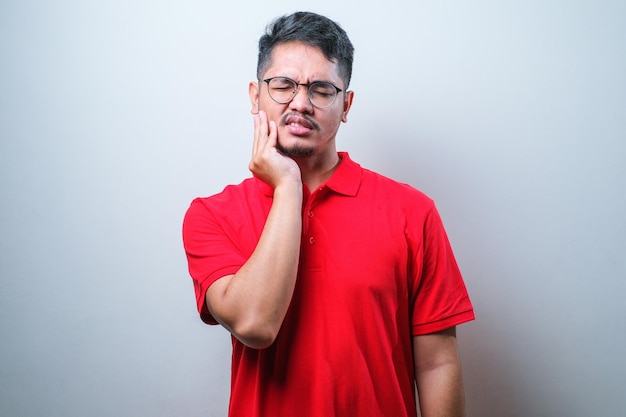 Joven y apuesto hombre asiático con pantalones casual tocando la boca con la mano con expresión dolorosa debido a dolor de muelas o enfermedad dental en los dientes