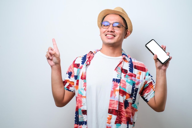 Joven apuesto hombre asiático que muestra la pantalla del teléfono inteligente muy feliz señalando con la mano y el dedo hacia un lado