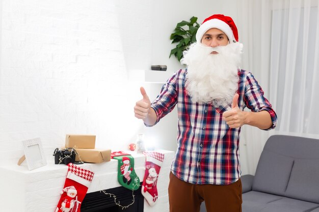 Joven apuesto hombre barbudo de santa claus con barba larga y sombrero de año nuevo, fondo de navidad