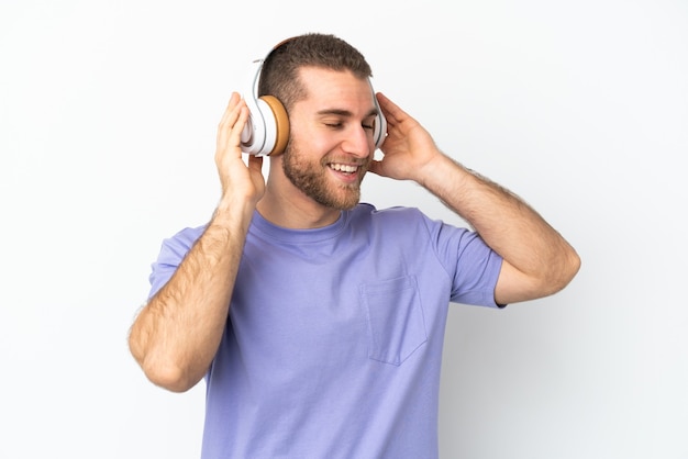 Foto joven apuesto hombre caucásico aislado en blanco escuchando música y cantando