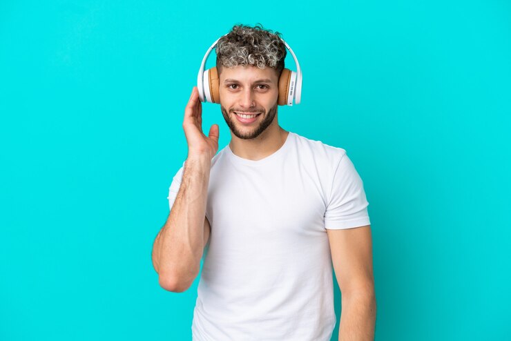 Foto joven apuesto hombre caucásico aislado sobre fondo azul escuchando música