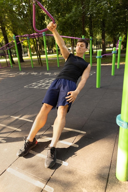 Un joven y apuesto hombre caucásico con ropa deportiva haciendo ejercicio en el campo deportivo en un brillante día de verano