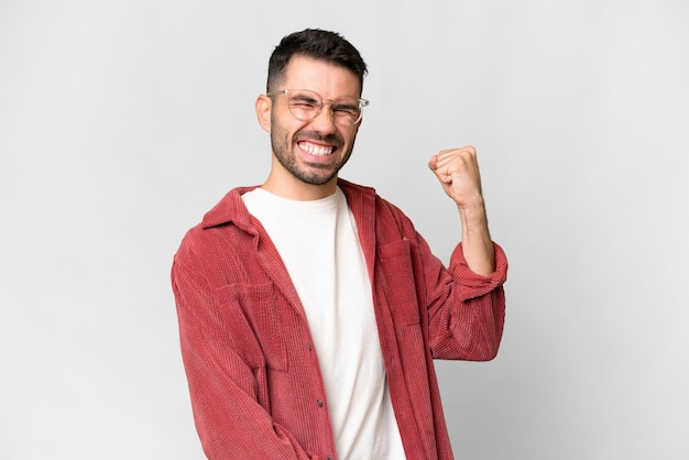 Joven apuesto hombre caucásico sobre fondo blanco aislado celebrando una victoria