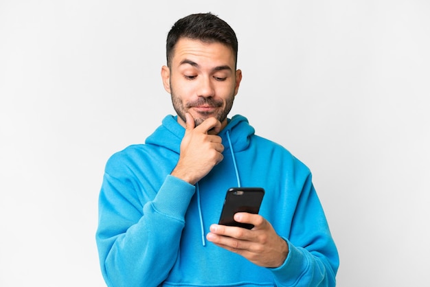 Foto joven apuesto hombre caucásico sobre fondo blanco aislado pensando y enviando un mensaje