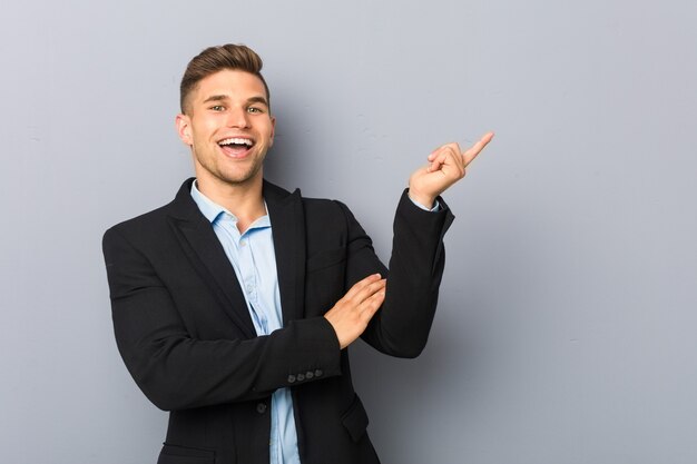 Joven apuesto hombre caucásico sonriendo alegremente apuntando con el dedo índice.