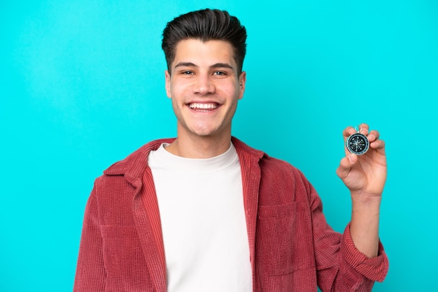 Joven apuesto hombre caucásico sosteniendo brújula sonriendo mucho