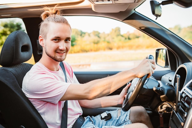 Joven apuesto hombre confiado conduciendo coche viaje por carretera