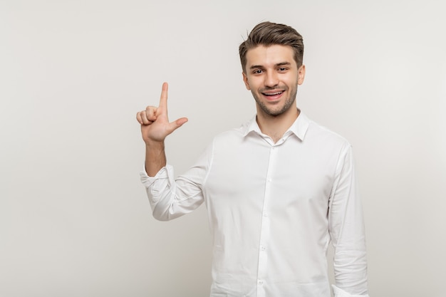 Foto joven apuesto hombre feliz sobre fondo blanco aislado mostrando dos dedos mientras sonríe