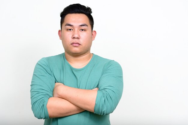 Joven apuesto hombre filipino con sobrepeso contra la pared blanca