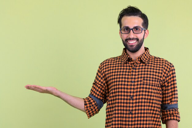 Joven apuesto hombre hipster persa barbudo contra la pared de color