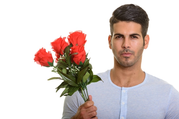 Joven apuesto hombre persa sosteniendo rosas rojas listas para San Valentín