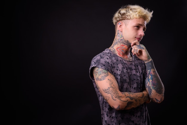 Joven apuesto hombre rebelde con cabello rubio y tatuajes