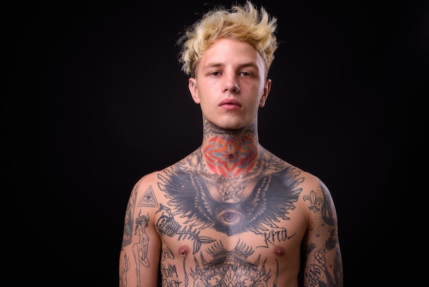 Joven apuesto hombre rebelde con tatuajes sin camisa