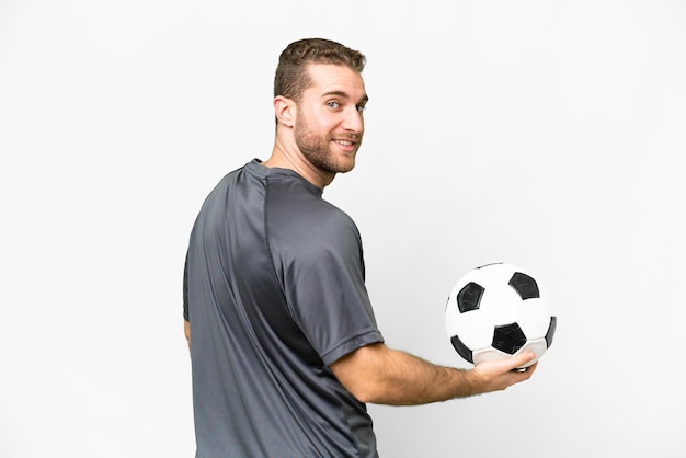 Joven apuesto hombre rubio sobre fondo blanco aislado con balón de fútbol